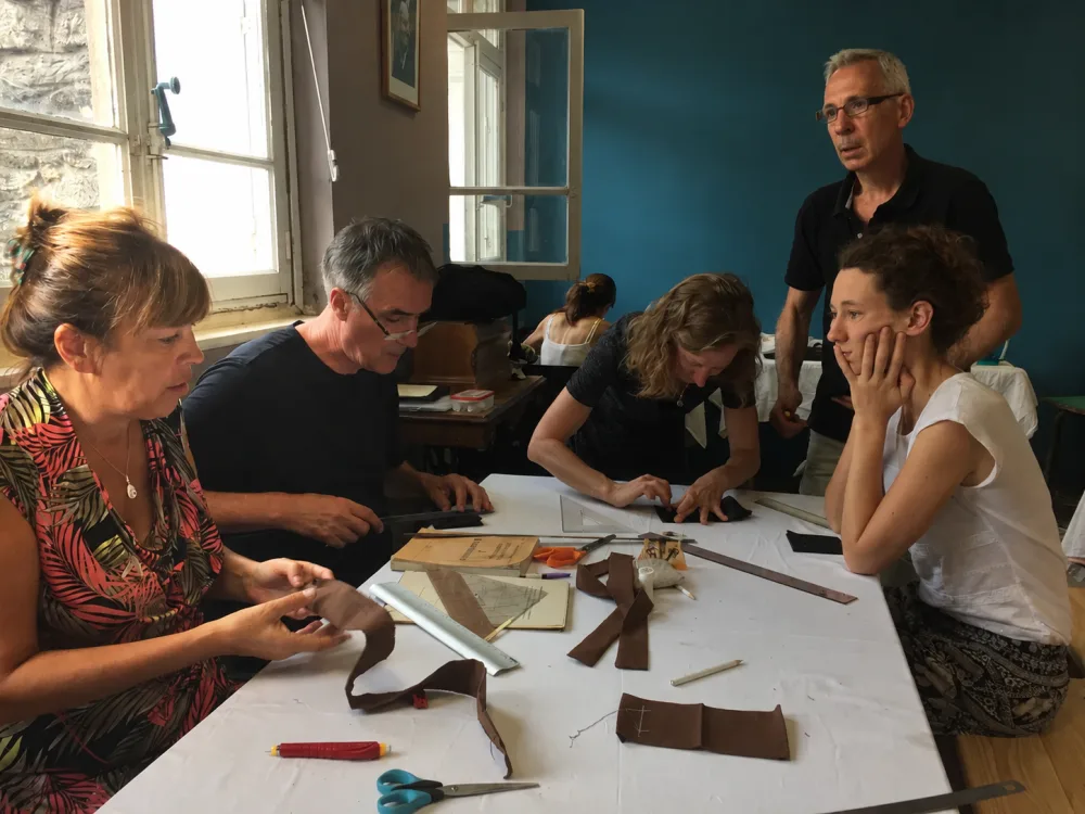 Participants au stage de couture du kesa de 2018 travaillant le tissu autour d'une table à l'atelier