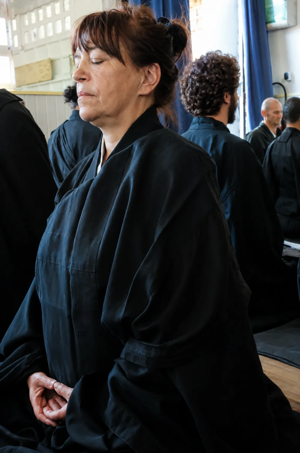 Véronique Myokan Harruis assise en zazen au temple Yujo Nyusanji, mains en mudra et yeux mi-clos, entourée d'autres pratiquants